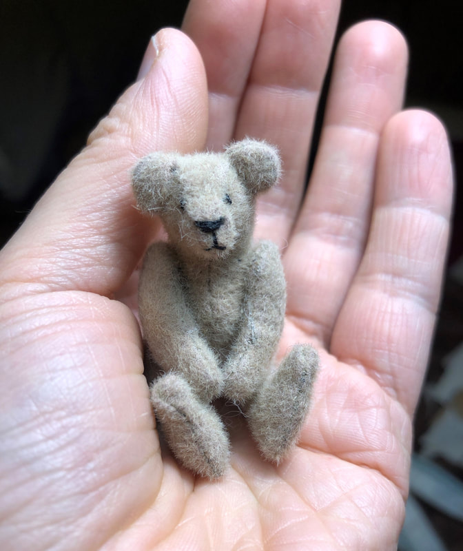 Very small teddy bear standing 5.5cm tall. Made from pale grey/brown fur and has movable arms and legs.